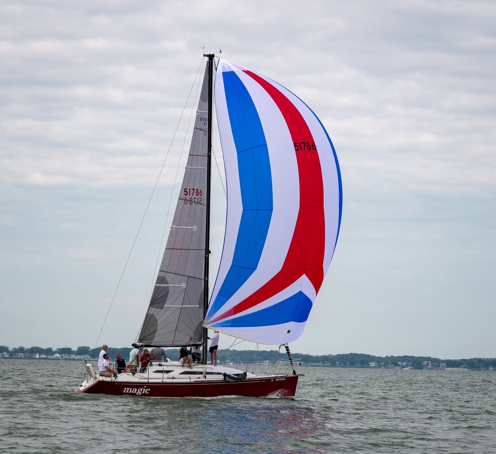 Magic sailing with a red, white, and blue spinnaker